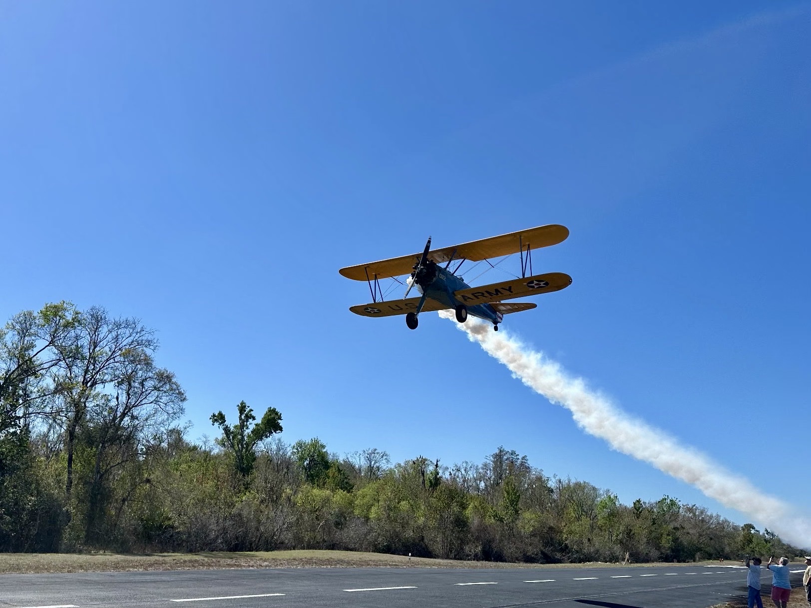 Stearman biplane taking off trailing smoke