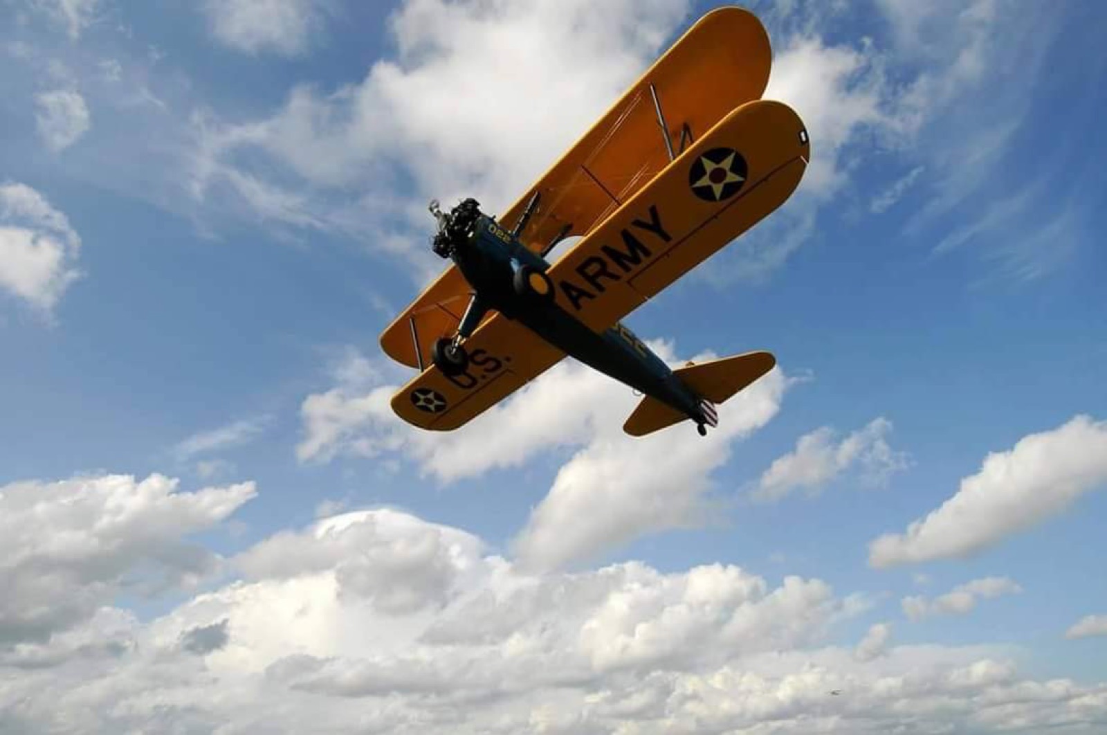 U.S. Army Stearman banking against a cloudy sky
